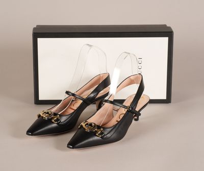 une paire de chaussures en cuir noir avec des boucles dorées et une boîte noire