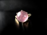 a close up of a pink stone ring on a black surface