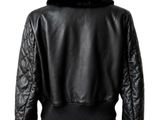 the back view of a woman wearing a black leather jacket and pink skirt