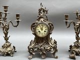 three candles and a clock sitting on a table