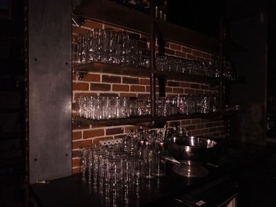 une étagère sur laquelle sont posés des verres à vin, à côté d'un mur en briques