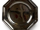 a silver plate on a stand with a reflection of a person in the mirror