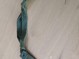 une ceinture vert olive avec une boucle en métal posée sur une surface en bois