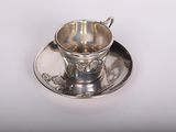 une tasse et une soucoupe en argent posées sur une soucoupe
