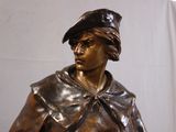 a bronze statue of a woman with a hat on her head