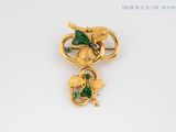 an image of a gold brooch with green leaves on it