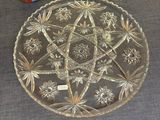 a glass plate on the floor next to a vase