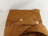 brown quilted comforter on a white bed with a white pillow
