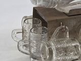 a bottle and glasses on a table with a wooden stand