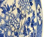 a blue and white plate with a bird and flowers on it