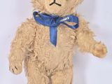 un ours en peluche marron avec un nœud bleu autour du cou