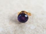 an image of a gold ring with a purple stone in it