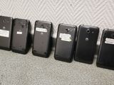 several cell phones lined up against a wall with tags on them