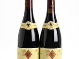 two bottles of red wine sitting next to each other on a white surface