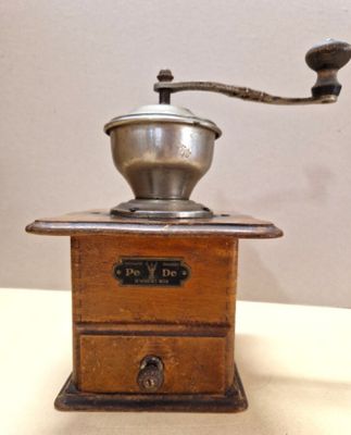 a coffee grinder on a table with a cup on it