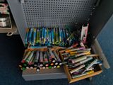 many pens and pencils in a box on the floor