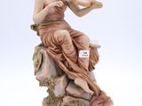 statue d'une femme assise sur un rocher, un violon à la main