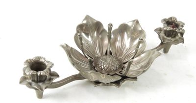 une assiette en argent ornée d'une fleur sur un fond blanc