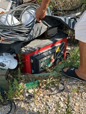 un homme debout à côté d'un tas d'appareils électroniques au bord de la route