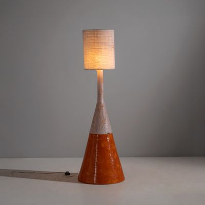 une lampe de table orange et blanche, surmontée d'un abat-jour blanc