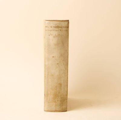 un vieux livre posé sur une table à côté d'un mur blanc