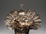 an ornate silver vase with a cross on top of it