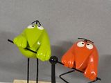 three colorful birds that are sitting on a wooden stand