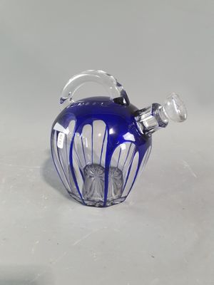 une théière en verre bleu avec une anse, posée sur une surface blanche