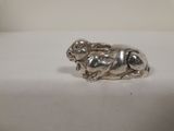 une image représentant une figurine en argent en forme de chien posée sur une surface blanche