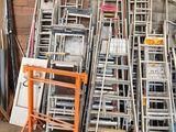 many chairs and ladders stacked up against a brick wall