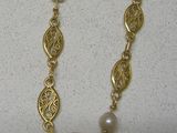 collier plaqué or orné de perles et de motifs en filigrane sur fond blanc