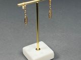 gold plated earrings on a marble stand with a chain