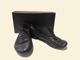 pair of black leather shoes sitting on top of a black box