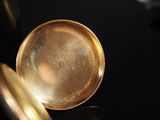 a close up of a gold pocket watch on a black surface