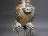 a bronze vase on a stand with two elephants on it