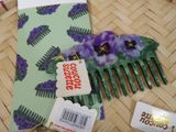 a green comb with purple flowers and a tag on it
