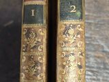 two old books sitting on top of a wooden table next to each other