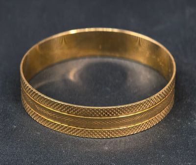 gros plan d'un bracelet en or sur une surface noire