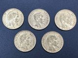 quatre pièces d'argent de tailles et de formes différentes sur un fond bleu
