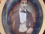 an old photo of a man in a tuxedo sitting in a chair