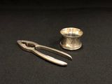 une coupe en argent et une pince posées sur une table noire