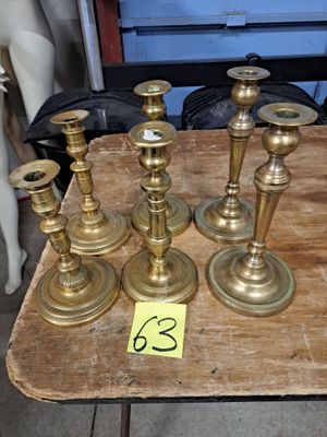 Plusieurs bougies en laiton sont posées sur une table en bois à côté d'un mannequin