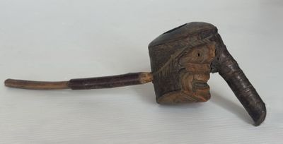 une vieille pipe posée sur une table blanche, à côté d'un bâton en bois