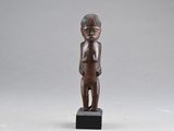 une petite statue en bois représentant un garçon coiffé d'un chapeau