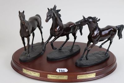 three statues of horses running on a wooden base