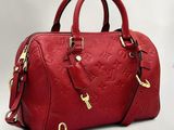 un sac à main Louis Vuitton rouge avec des finitions dorées