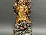 a gold statue of a woman with a dragon on her arm
