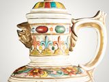a white and gold teapot with a painting on it