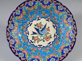une image représentant une assiette bleue et rouge sur laquelle figure un oiseau