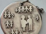 a silver pendant with a picture of a family on it